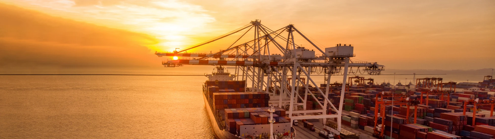 Crane loading cargo container at sunset