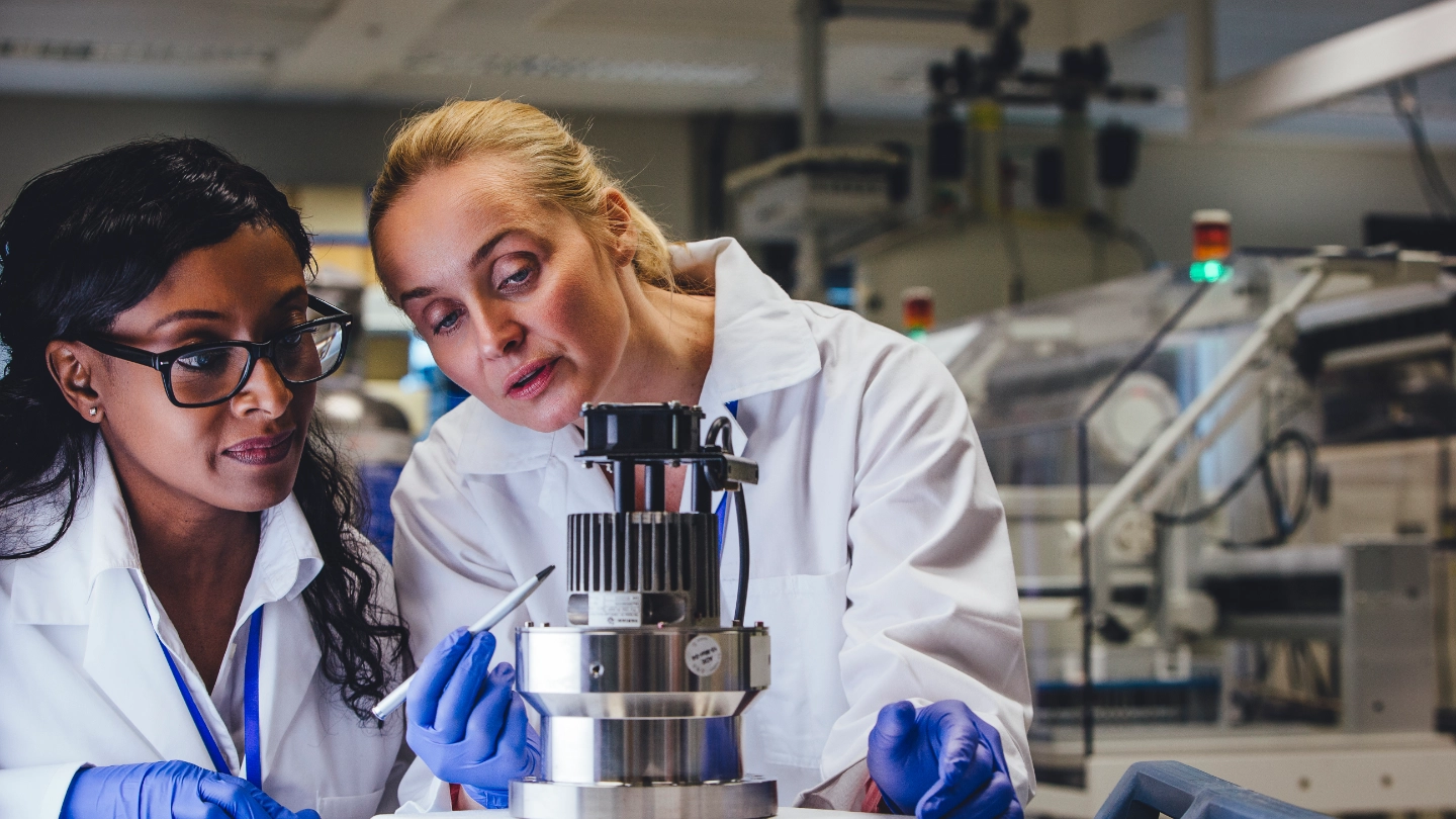 Two female lab workers in white coats and gloves image